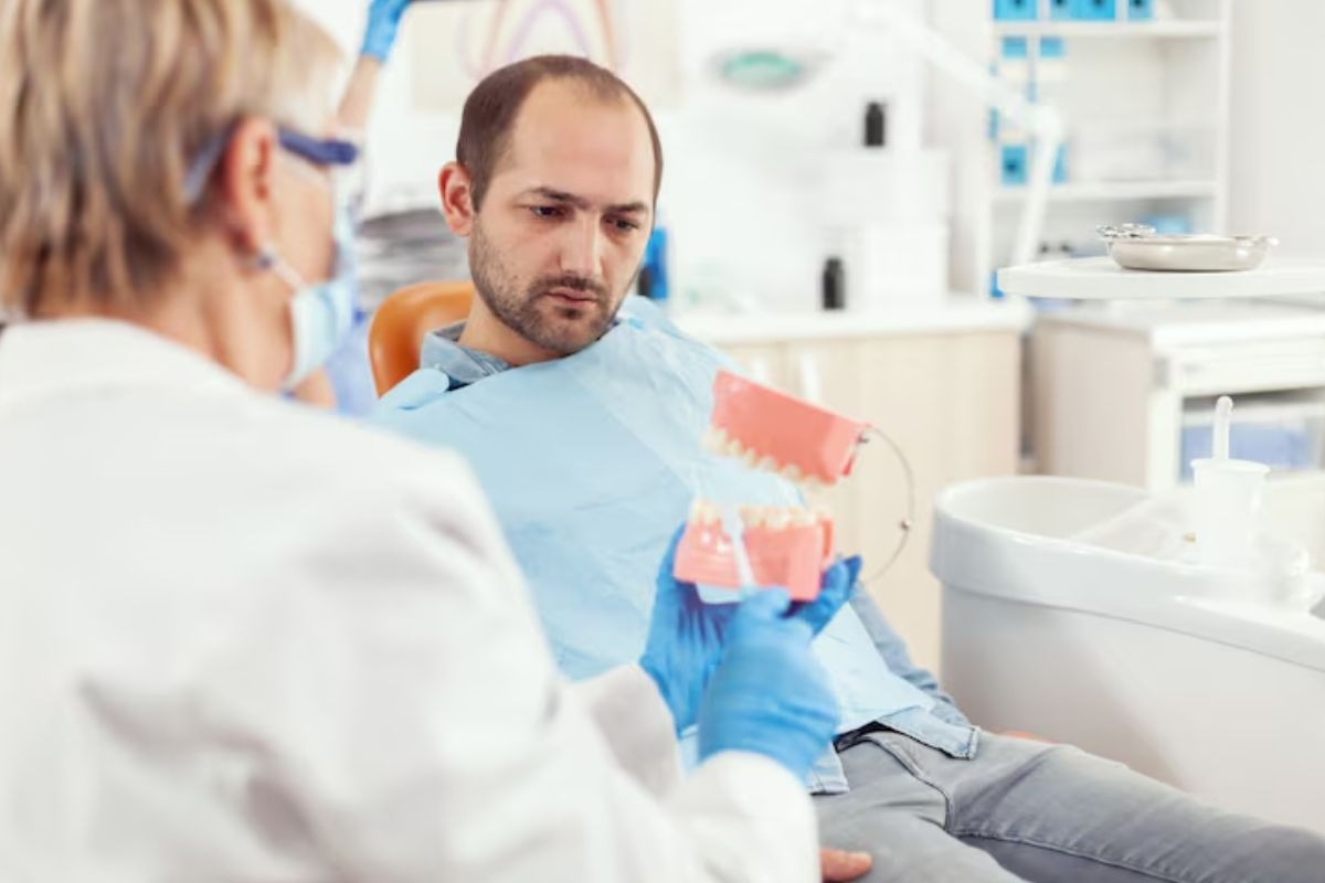 dentist explaining implant-supported dentures to a patient using a dental model.